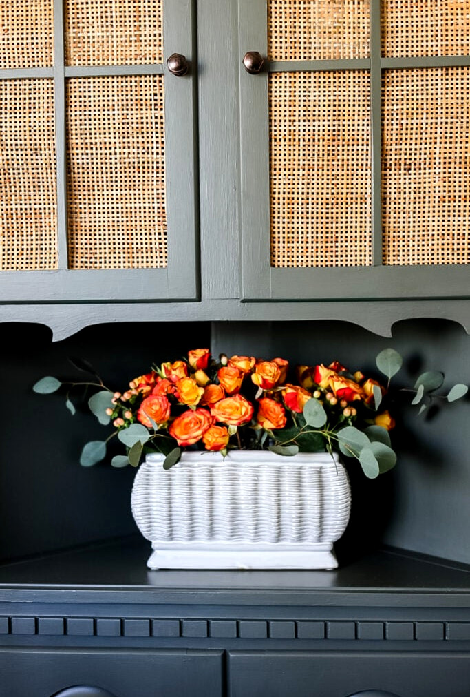 green hutch with orange rose display on shelf