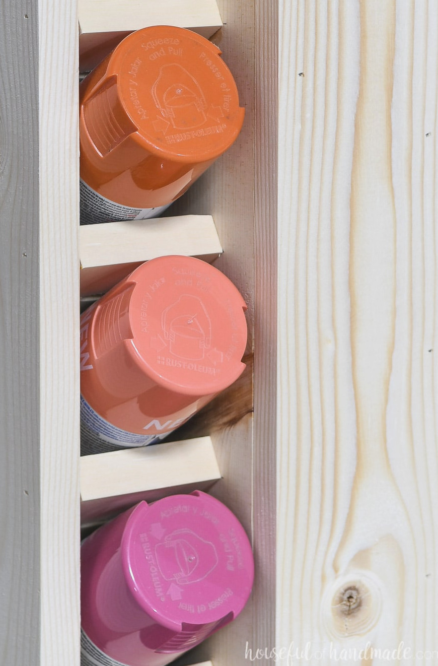 Close-up view of three paint cans placed in the spray paint storage slots.