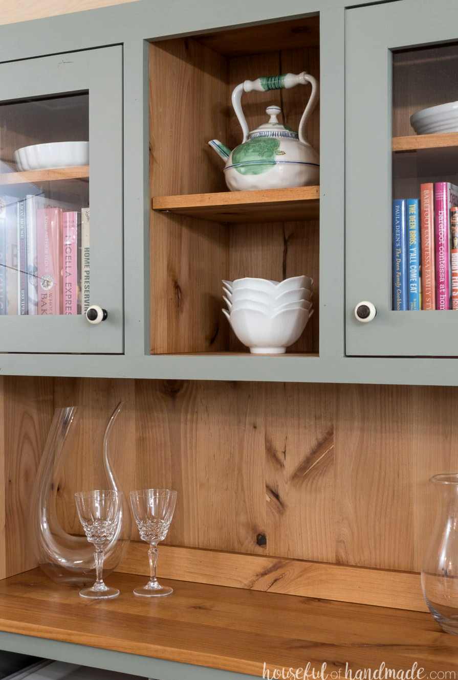 Detailed view of the natural wood featuring visible knots and grain inside the dining room hutch. The exterior is painted a warm gray. 