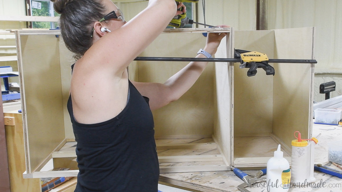 Installing support pieces along the upper back of the cabinet boxes.