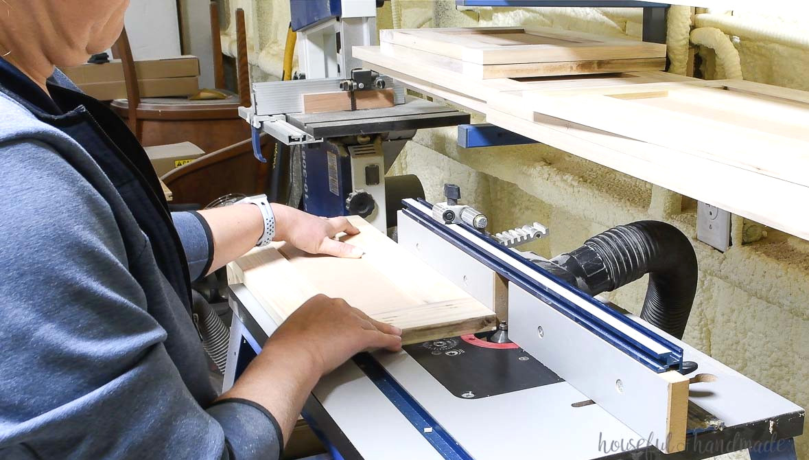 Using a router table to cut a chamfer on the cabinet doors.
