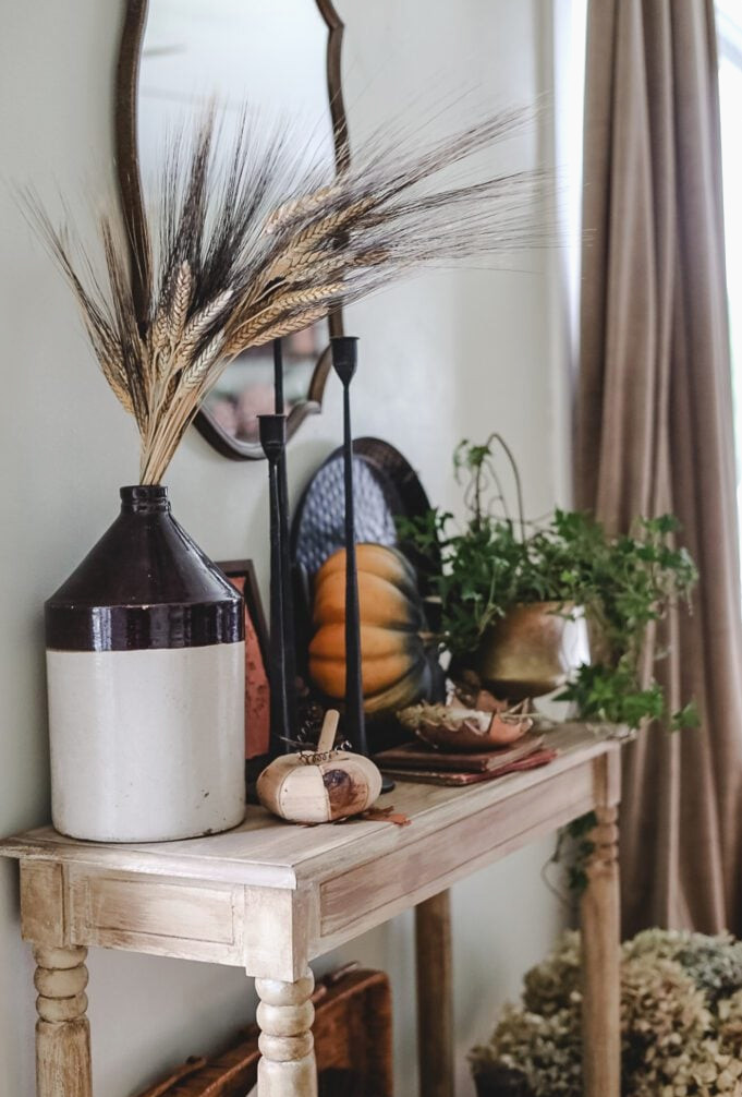entryway area decorated for Fall with vintage and thrift store finds plus plants and pumpkins
