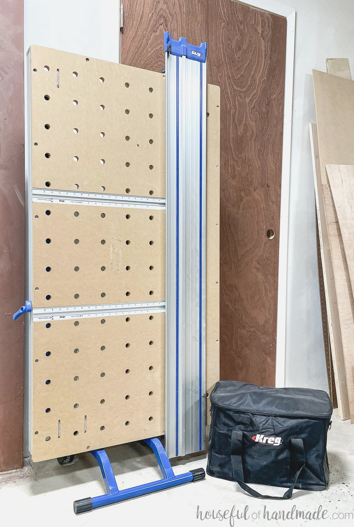 Kreg Adaptive Cutting System table folded and leaned against a wall, with the plunge saw in its bag beside it. 