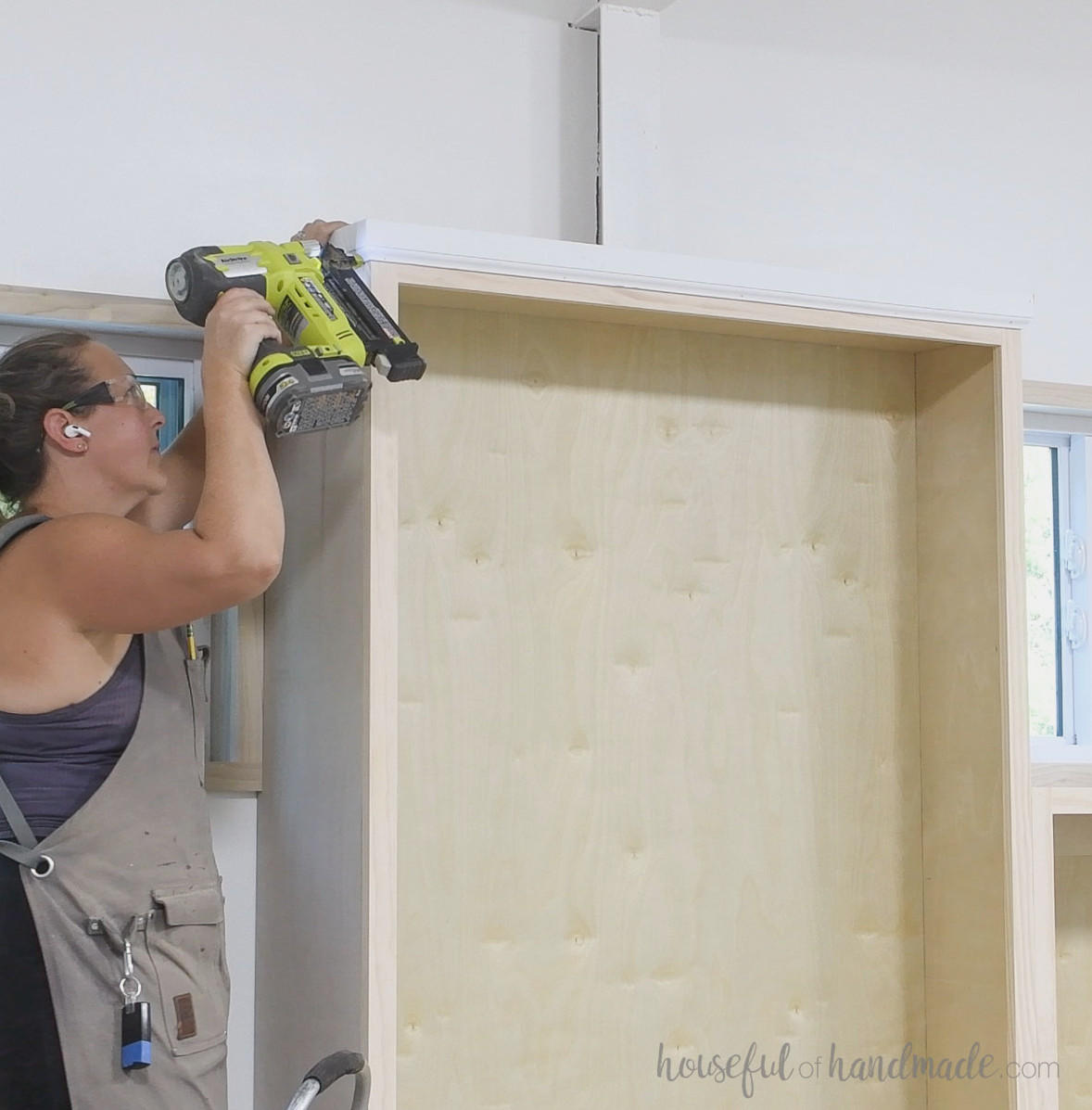 Installing moulding along the tops of the tall bookcases.