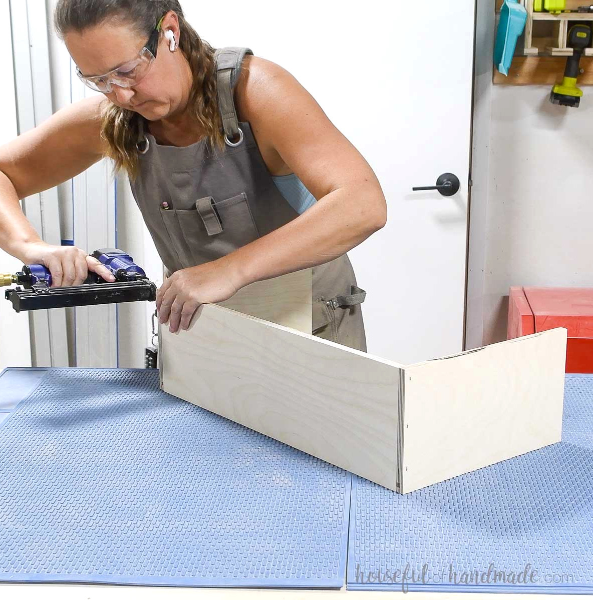 Fastening the drawer box front between the sides with pneumatic staples. 