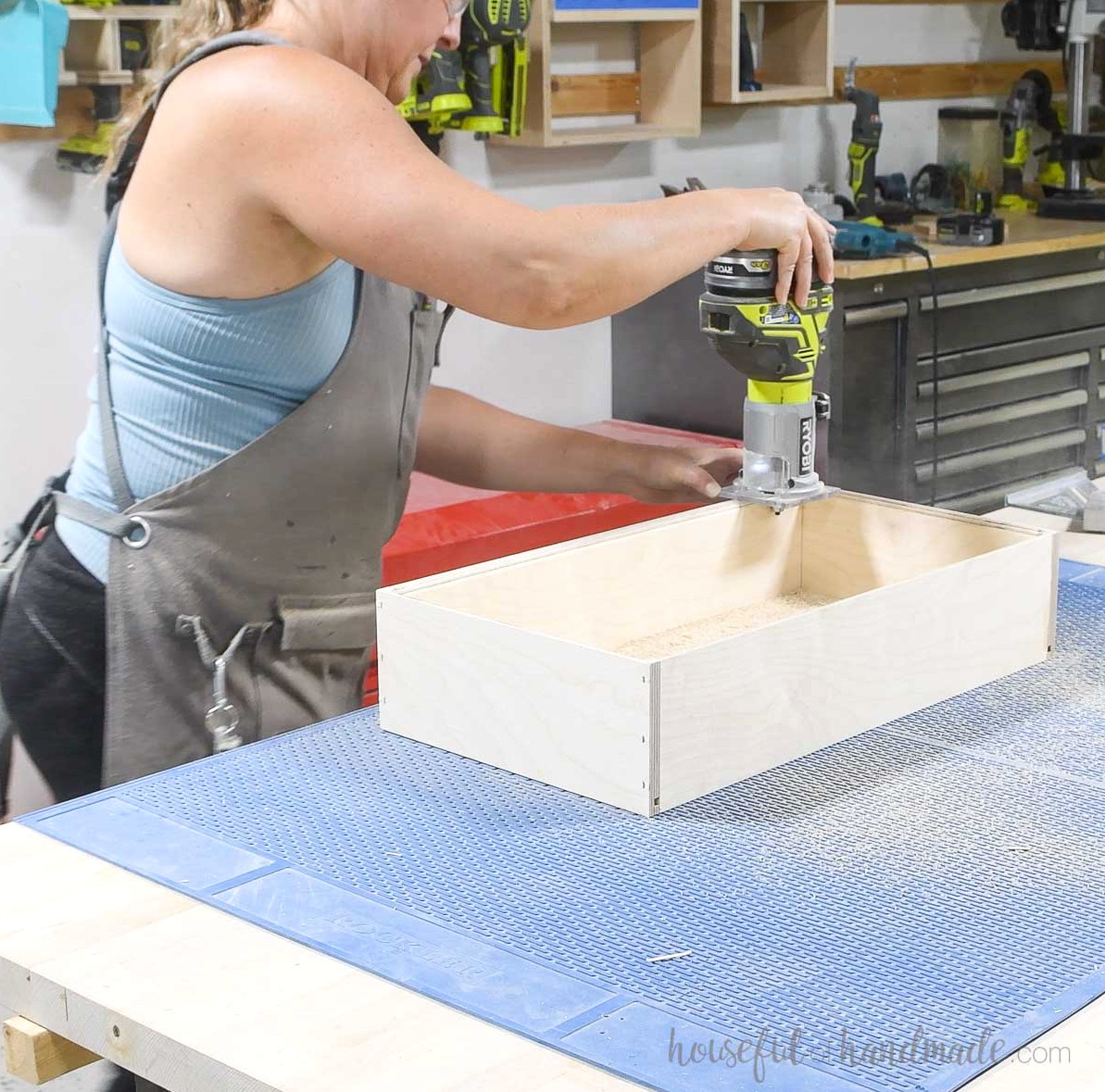 Rounding the plywood drawer box’s inside edge with a trim router. 