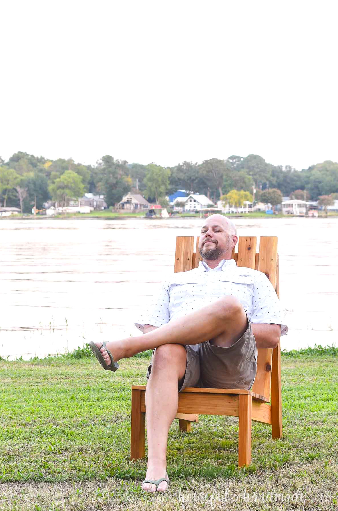 Tall man relaxing in the large Adirondack chair with his head against the back.