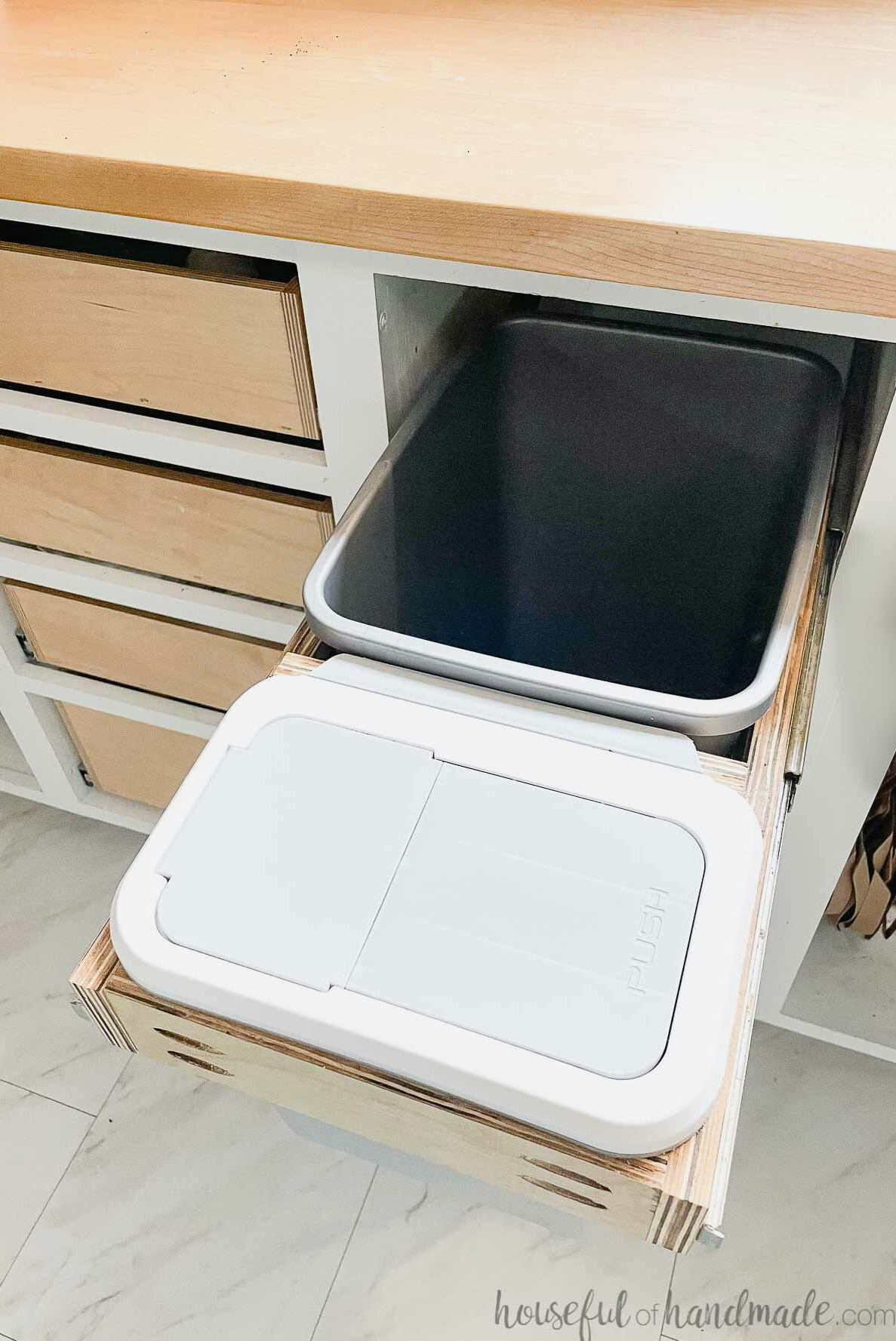 Looking down on a pull out trash can cabinet with a large garbage can and compost bin.