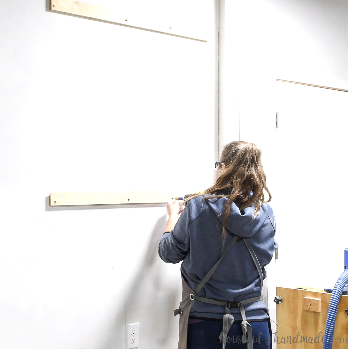 Attaching the other part of the french cleat to the wall into studs with countersunk screws.