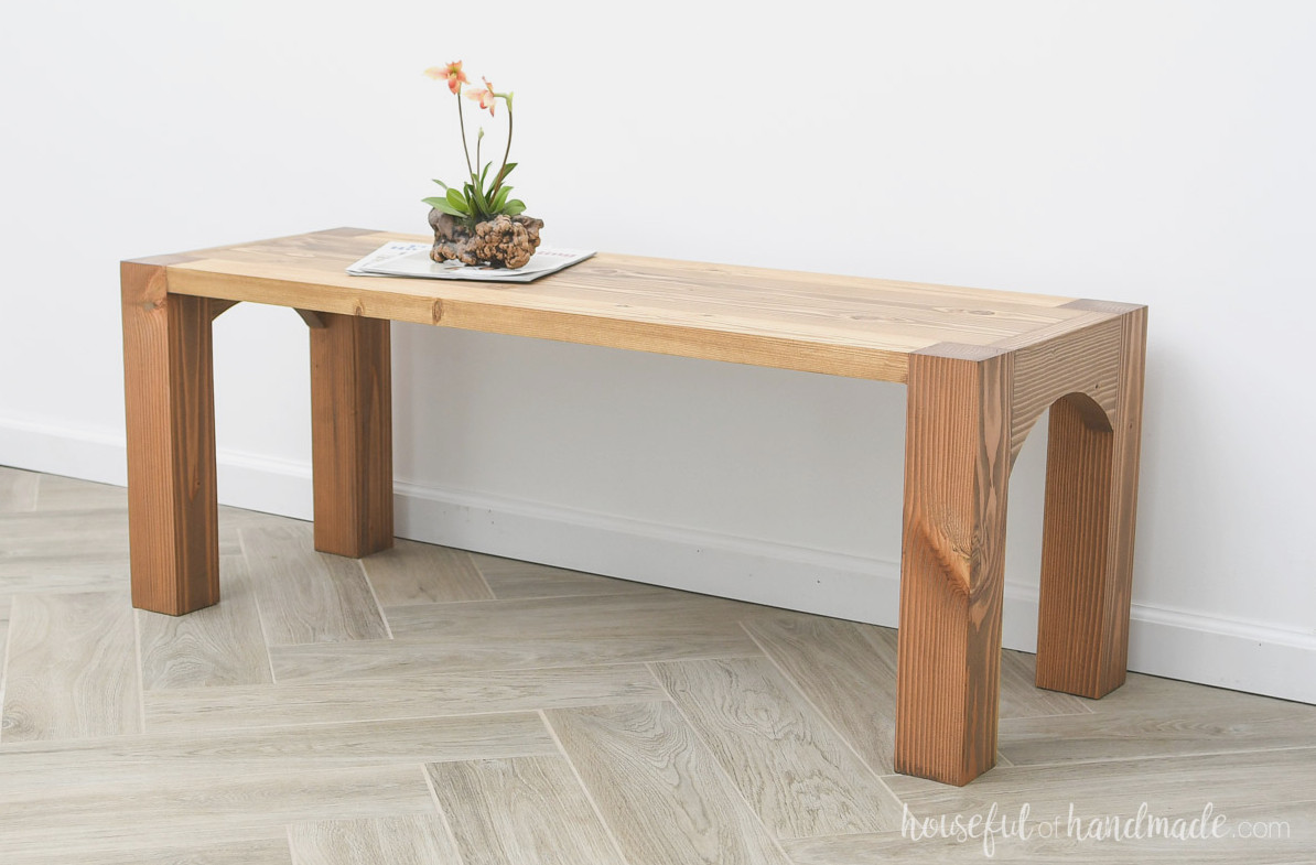 Solid wood single shelf coffee table with arches between the legs on the sides.