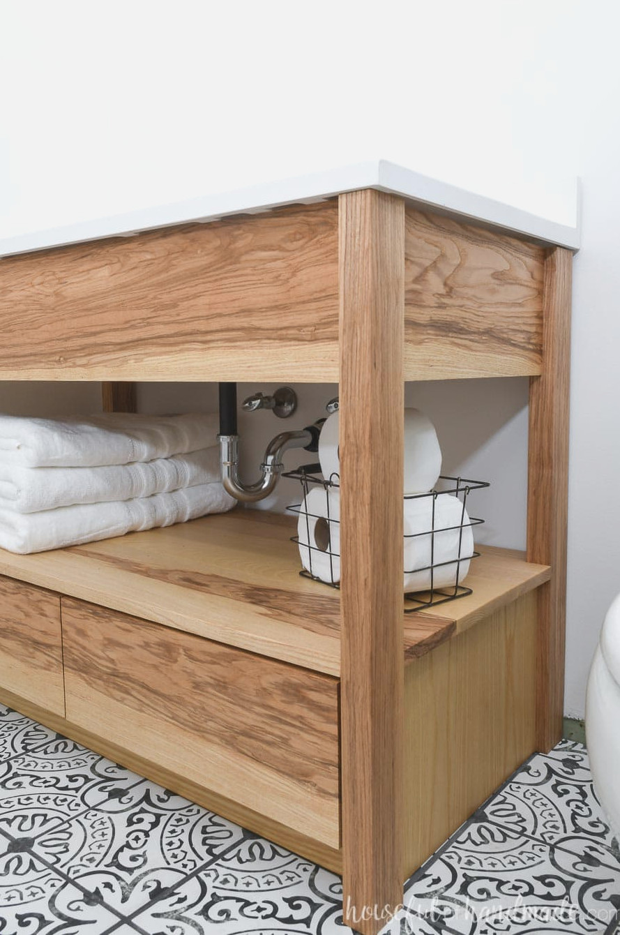 Detailed view of the open shelf on the DIY bathroom vanity, holding towels and toilet paper. 