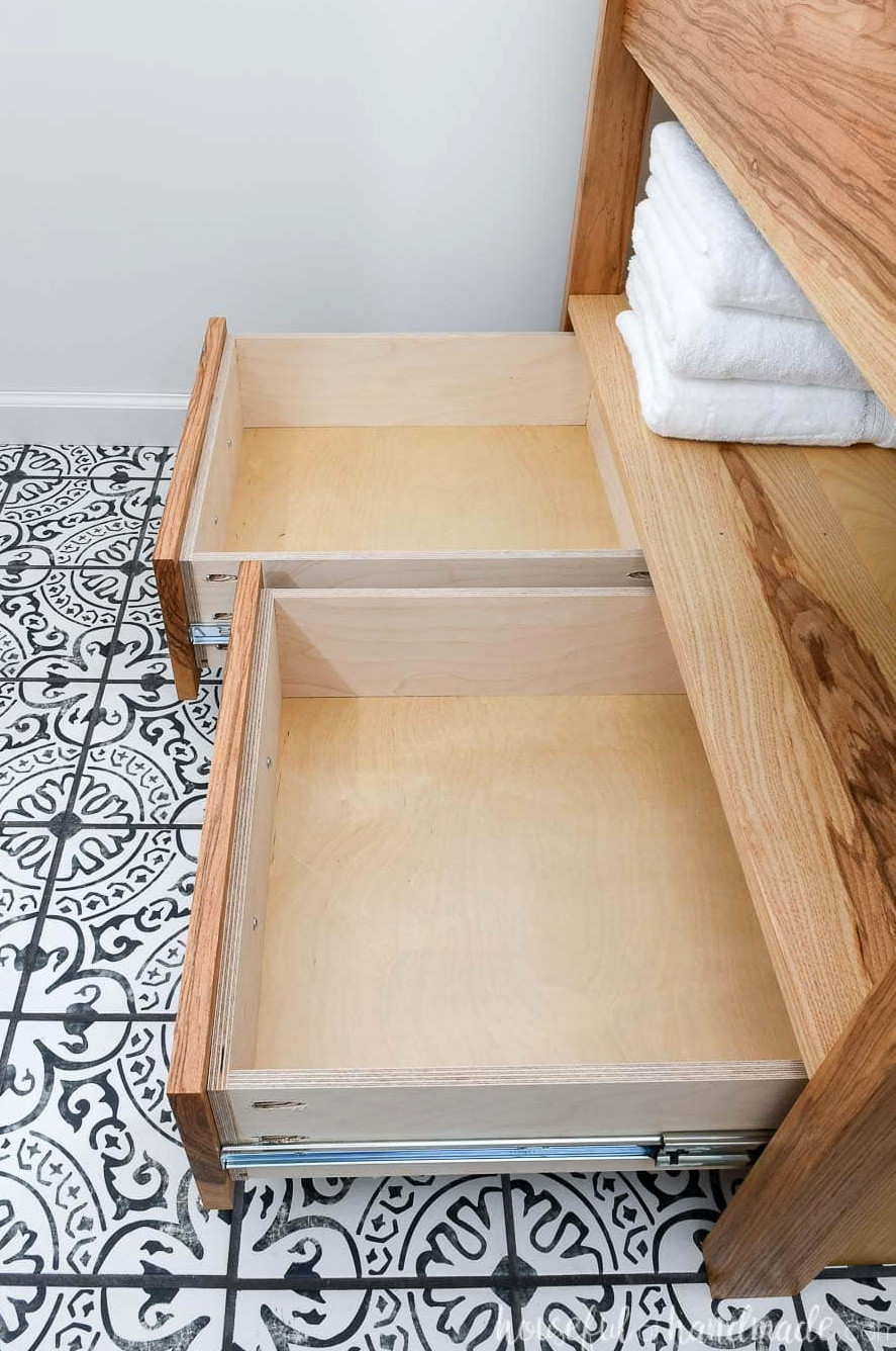 Open drawers on the modern bathroom vanity revealing the available storage area. 