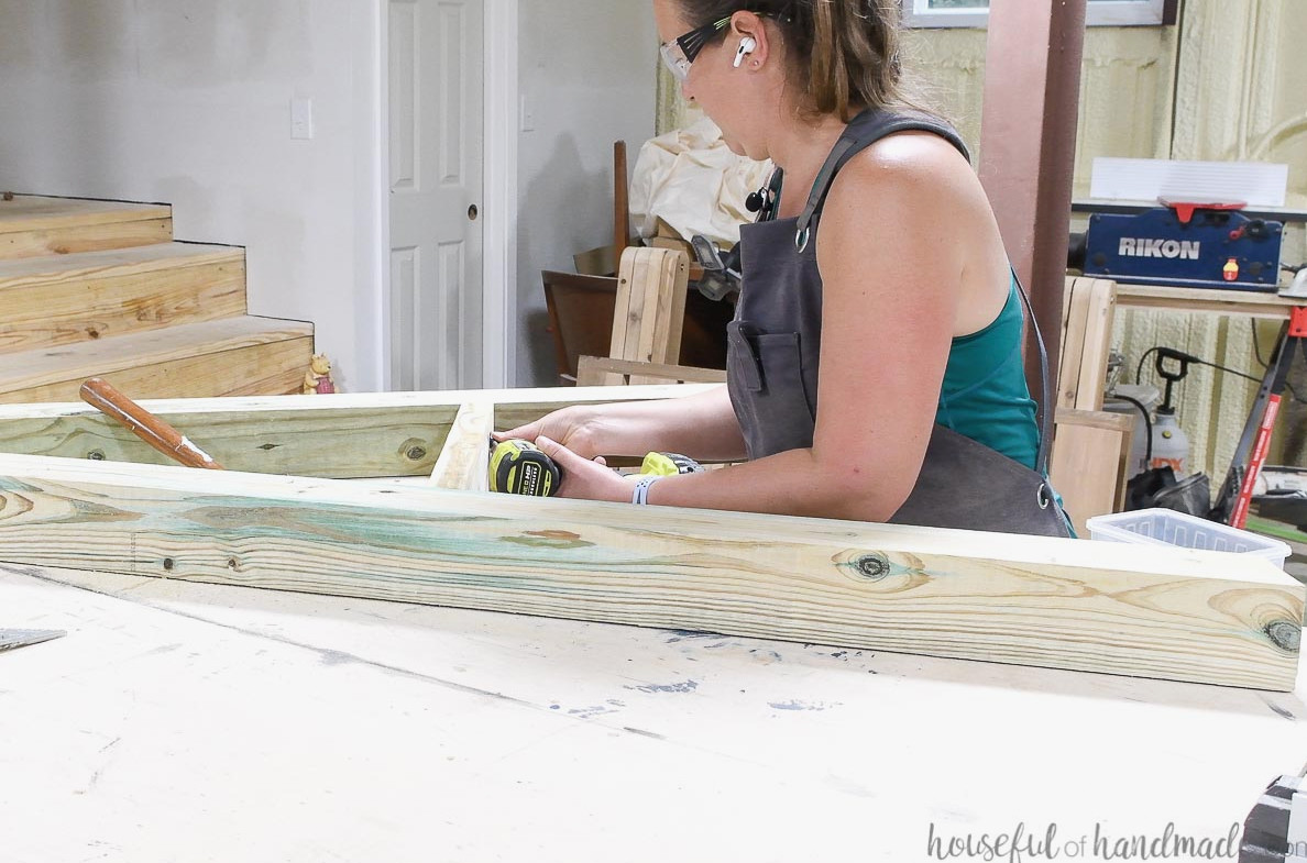 Fastening the 2x4 brace between the 4x4 legs of the hammock chair stand.