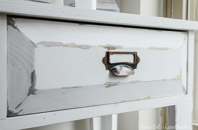 Create a lovely small console table for added storage and home decor. This DIY farmhouse console table features two spacious drawers and two shelves. An ideal storage solution for compact spaces. Housefulofhandmade.com Detailed view of the distressed finish on the farmhouse console table drawer fronts. Housefulofhandmade.com