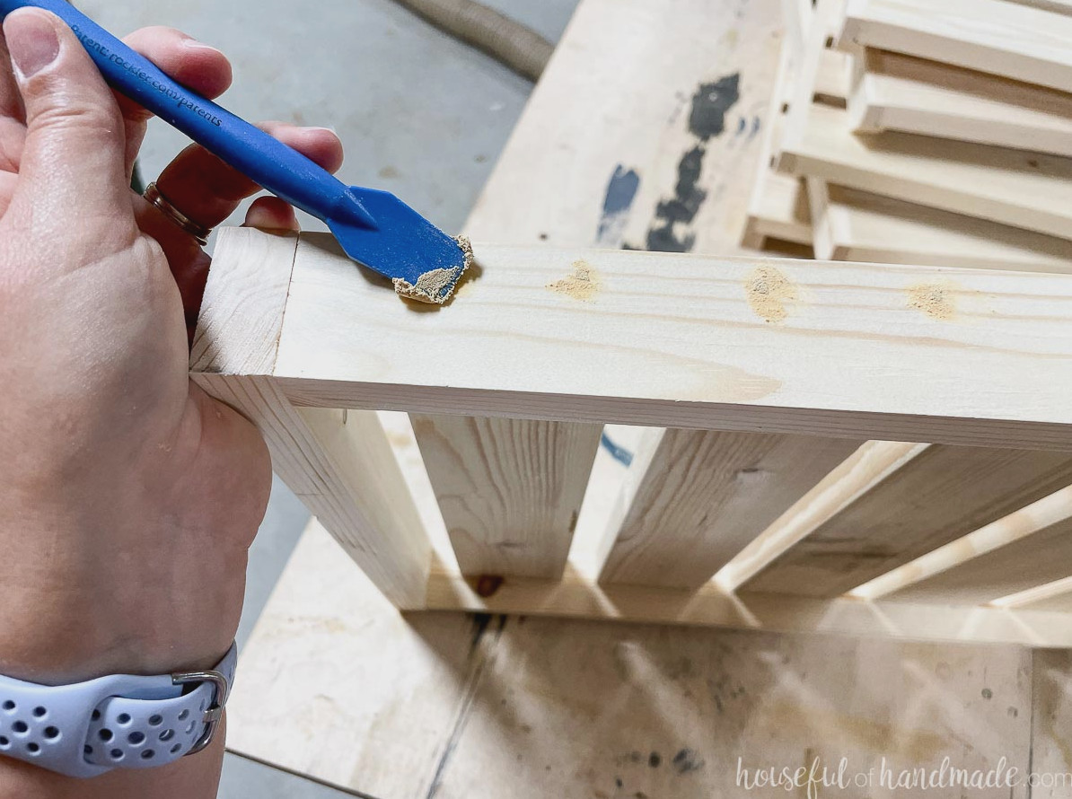 Applying stainable wood putty to the nail holes on the assembled shelf sides.