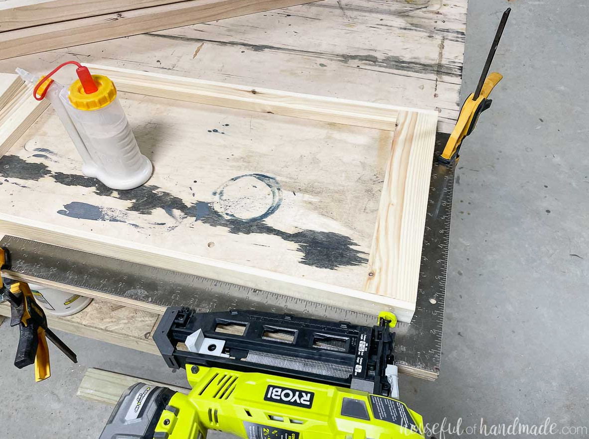 Fastening the front slat to the corner plant stand shelf with a nail gun.