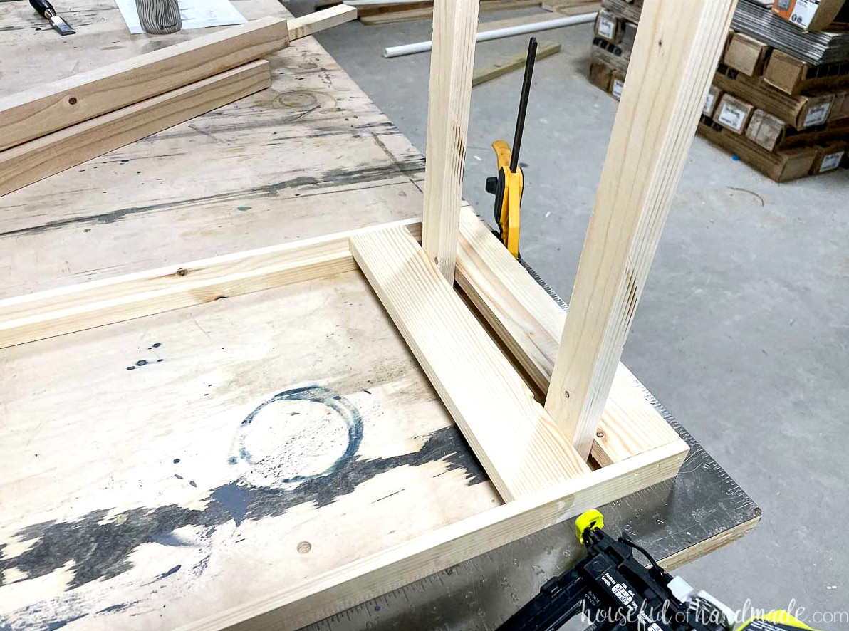 Securing the second slat to the plant shelf while using a wood scrap as a spacer.