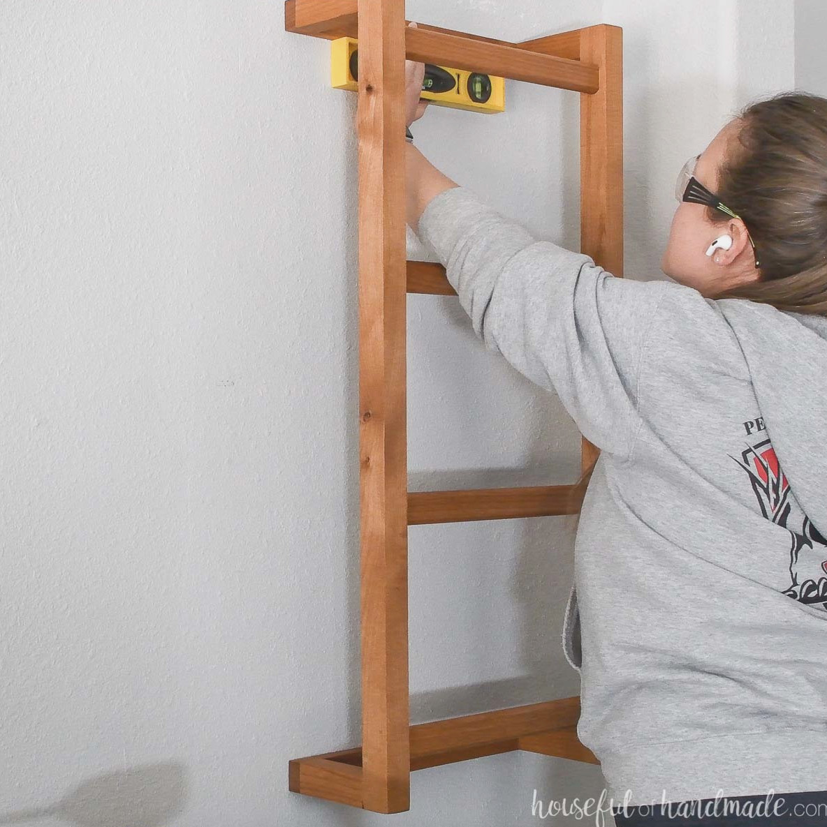Leveling the wall mounted ladder against the wall and marking the screw locations.