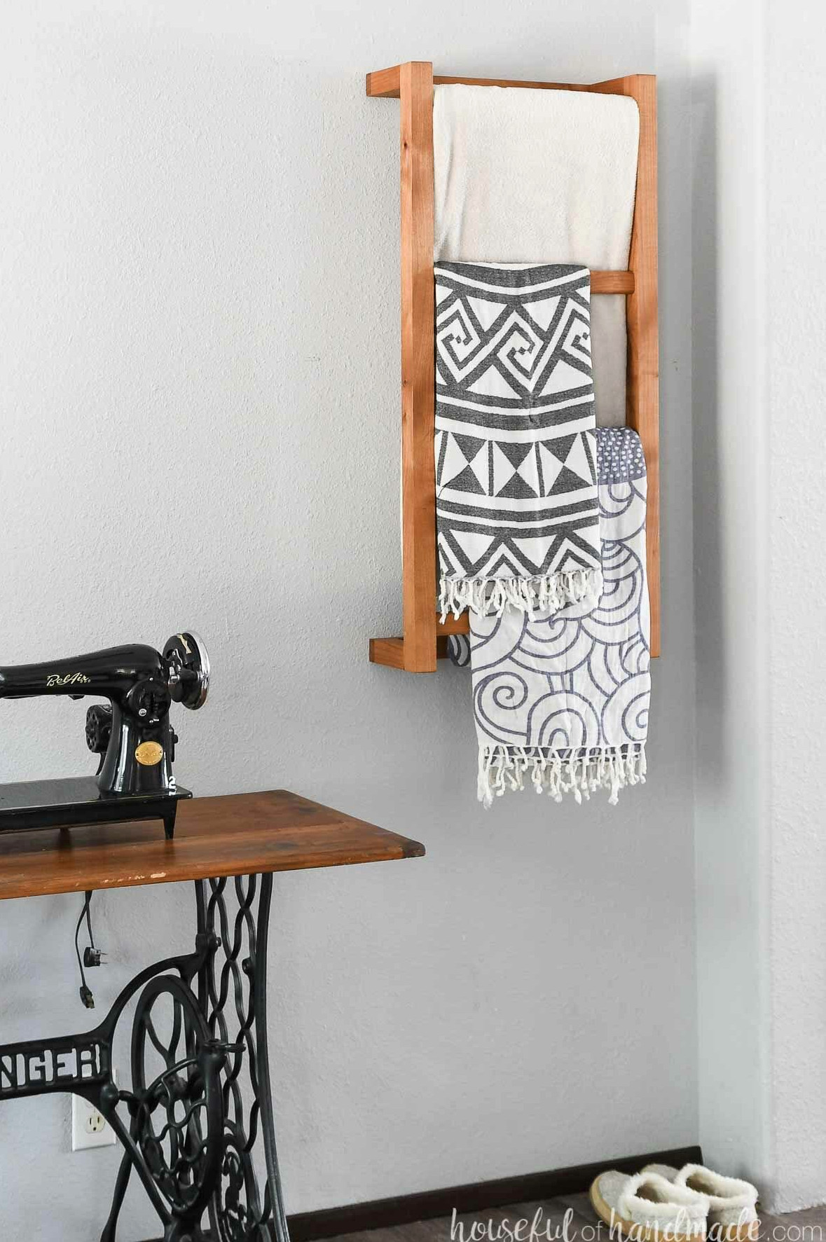 Bedroom featuring a wooden wall-mounted blanket ladder with blankets hanging from it and slippers on the floor.