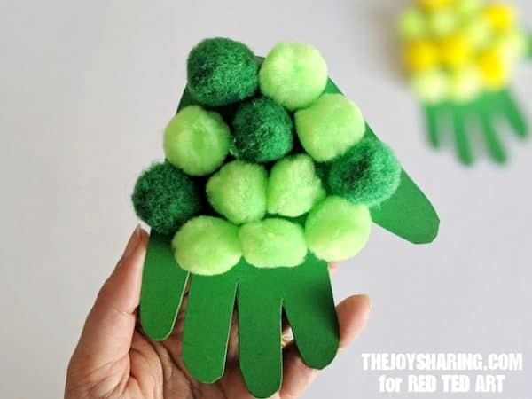 Paper hand cutout decorated with pom poms for a turtle shell