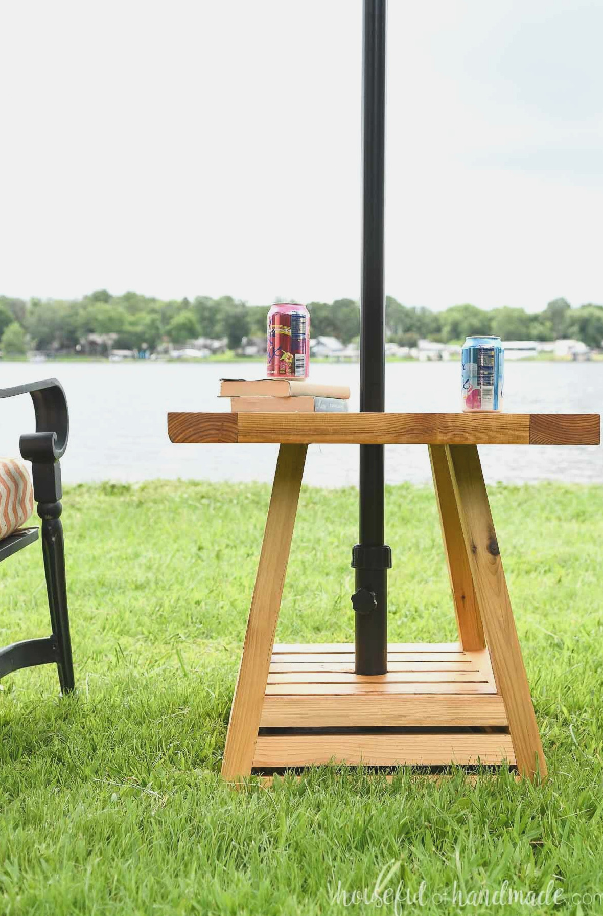 Close up of the outdoor side table with an umbrella made out of cedar wood in it in front of the lake.