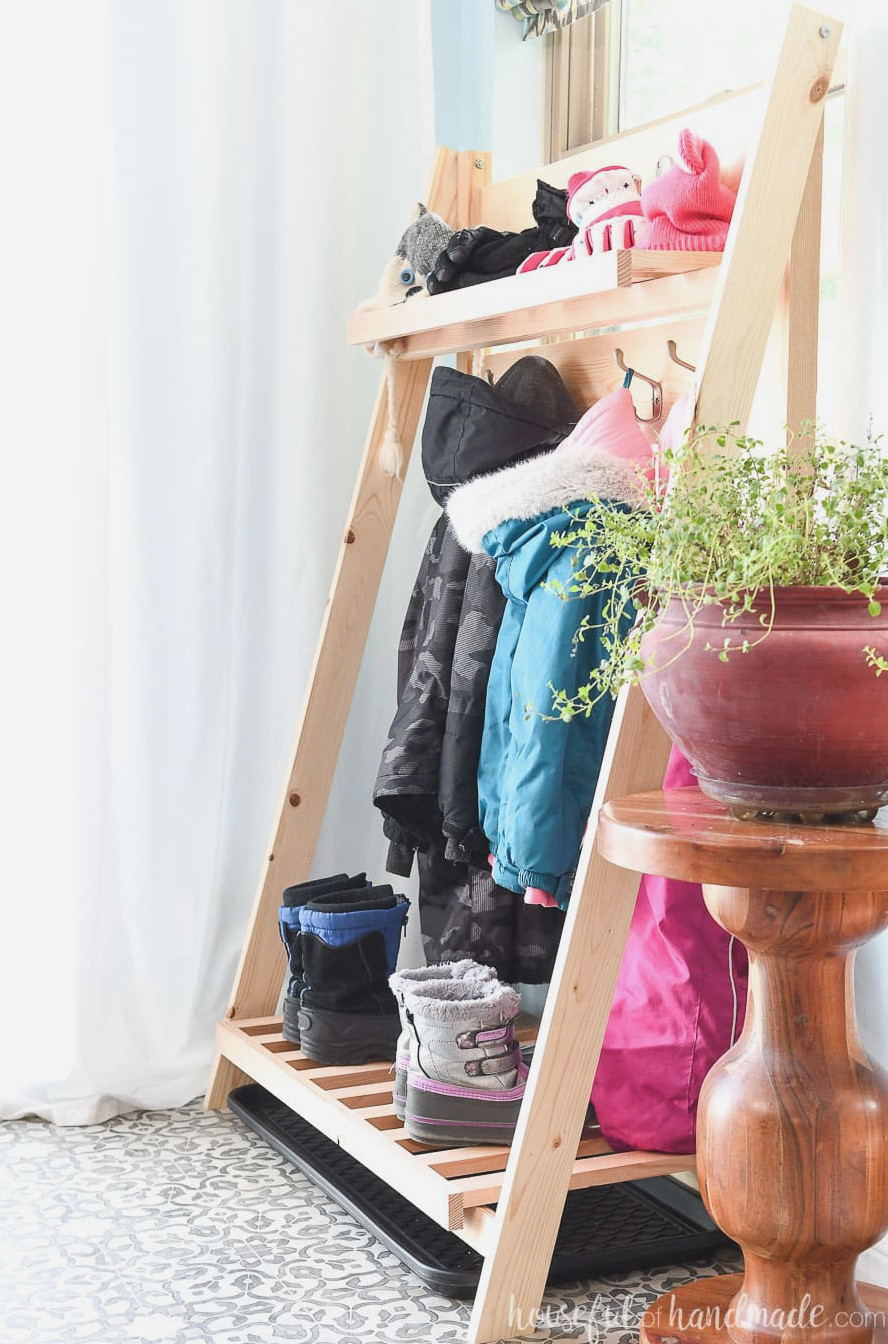 Side perspective of the collapsible storage shelves supporting children's snow pants, coats, gloves and boots while they dry.
