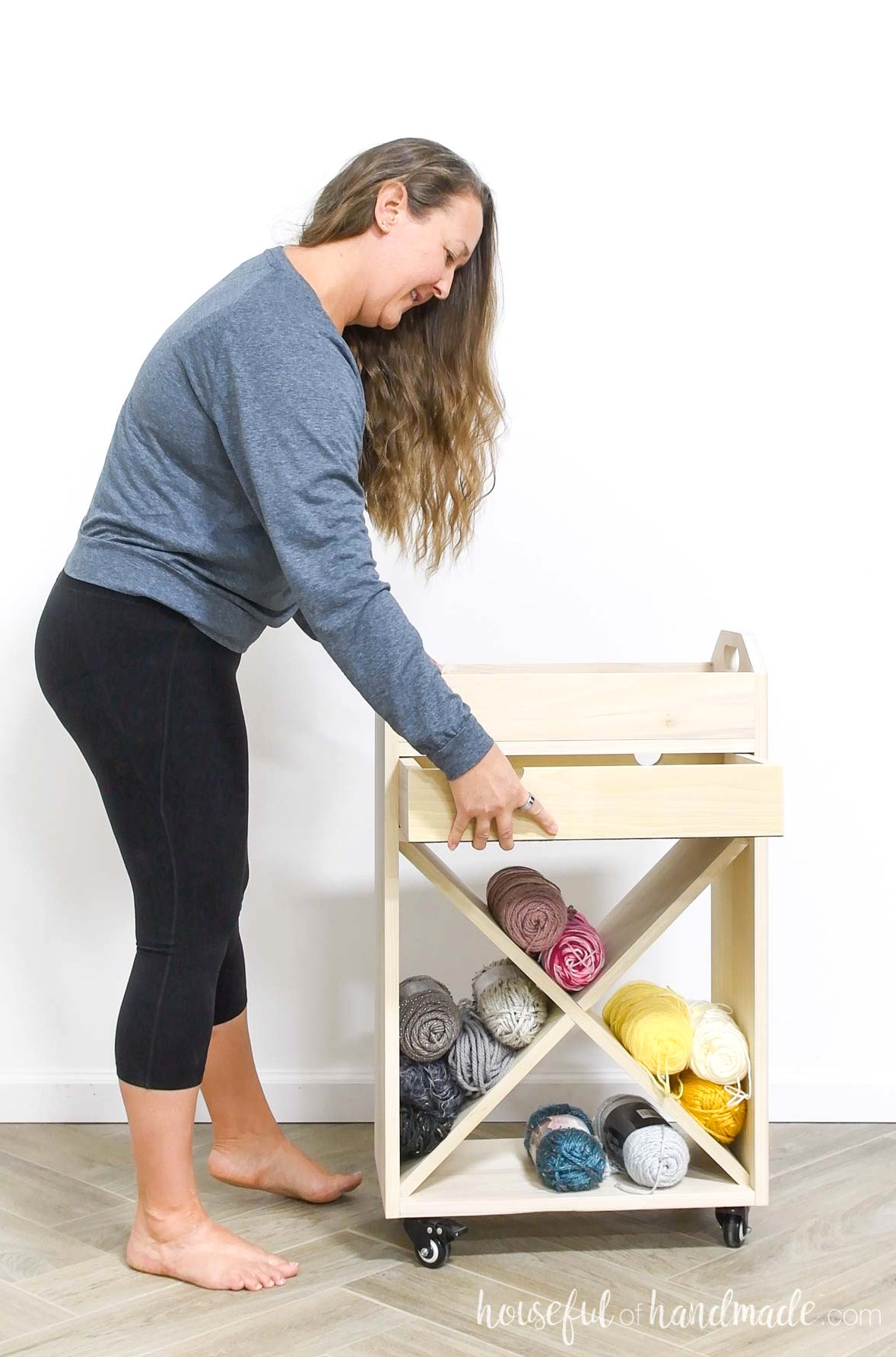 Kati standing beside a craft cart with yarn kept in the lower opening while pulling open the drawer.
