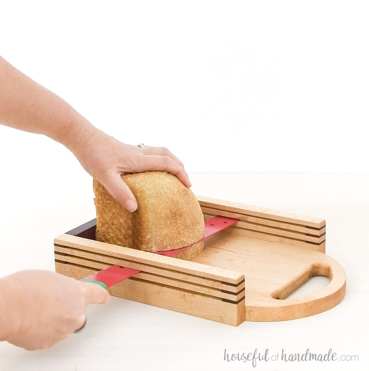 Cutting a sourdough loaf into slices with a wooden bread slicer.