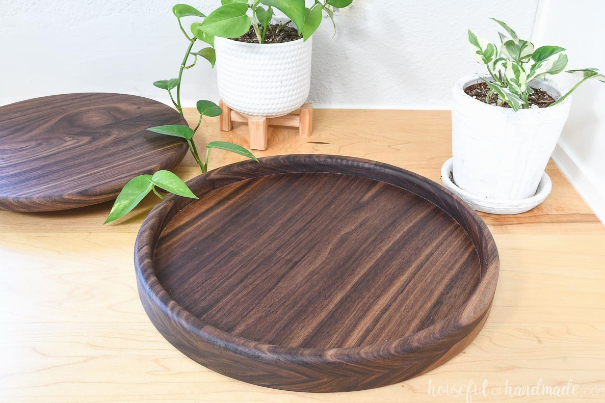 Walnut round tray with a smaller round tray made from the center scrap, displayed on a counter beside two plants.