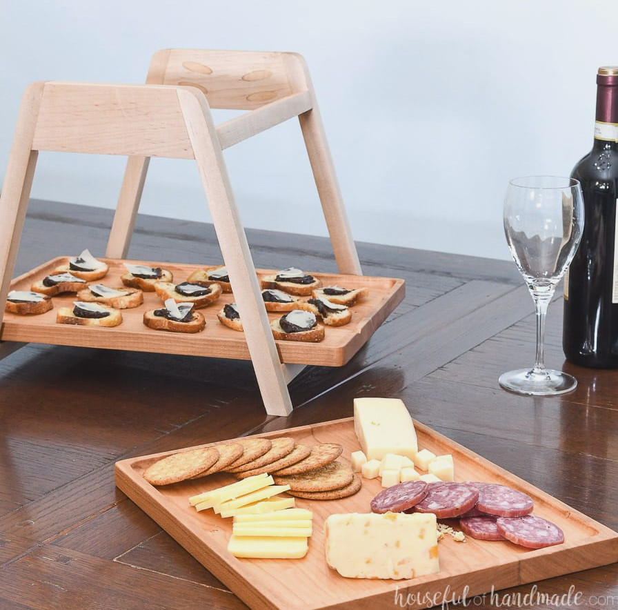 Wooden tiered serving stand on a table with its upper tray removed.