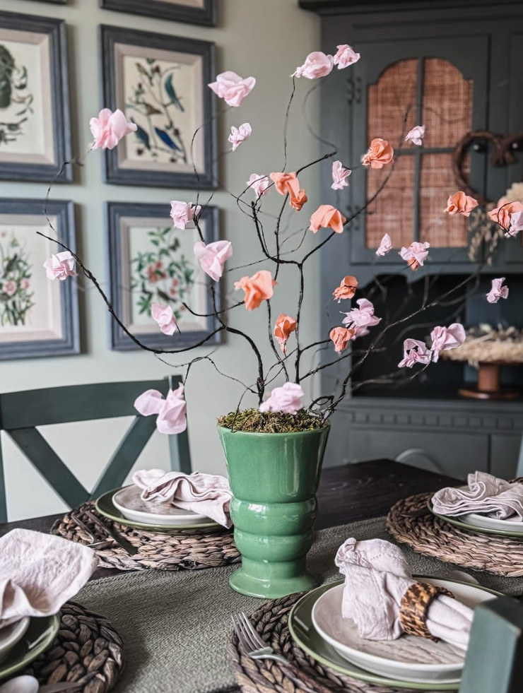 paper cherry blossom stems in green vase on dining table