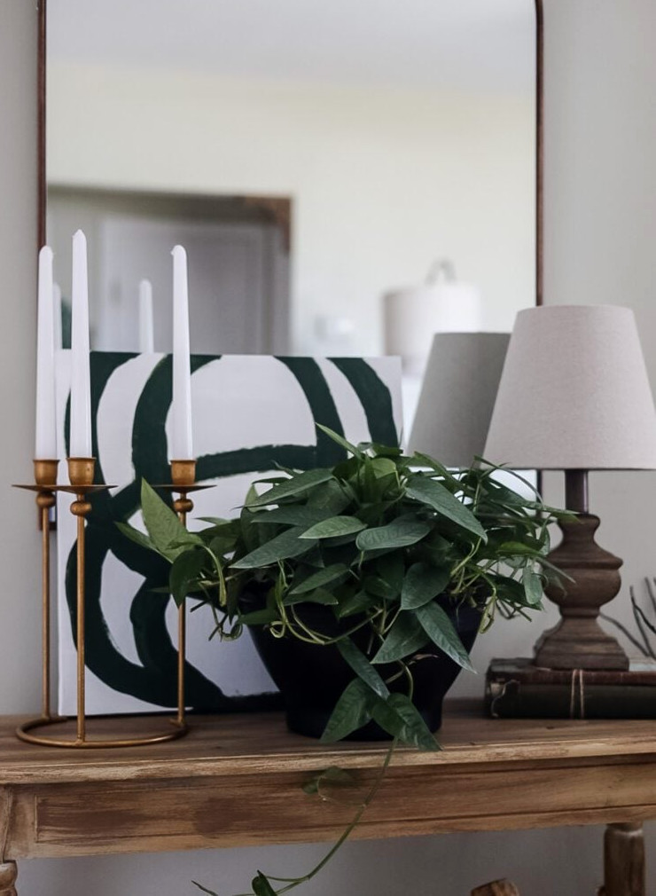entryway table with plant and brass candlesticks