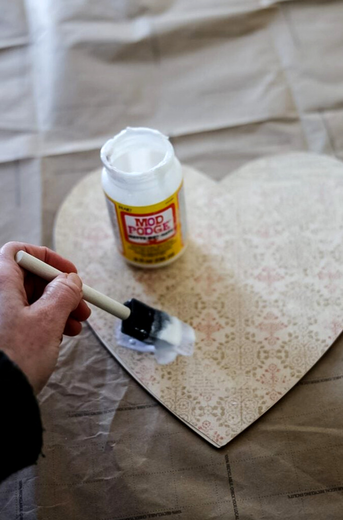 brushing mod podge on a heart diy project