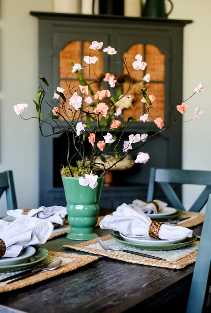 dining table with paper flowers in a green vase