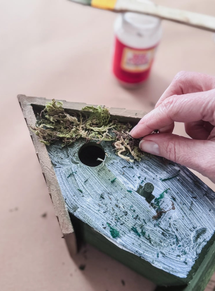 adding moss to a wood birdhouse