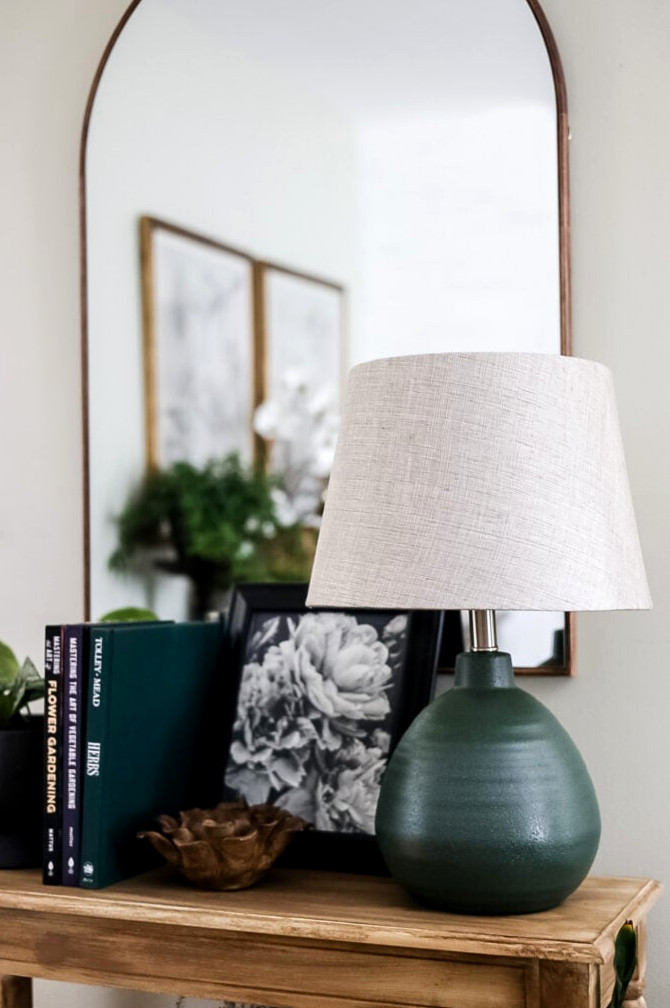 entryway table with green lamp and books