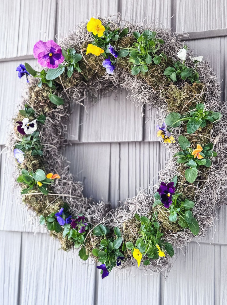 live pansy wreath hanging on a grey shingled house