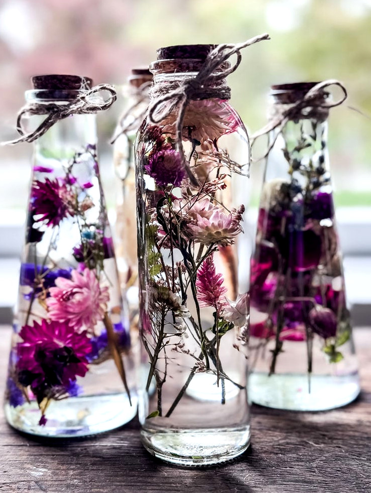 3 bottles of flowers suspended in oil