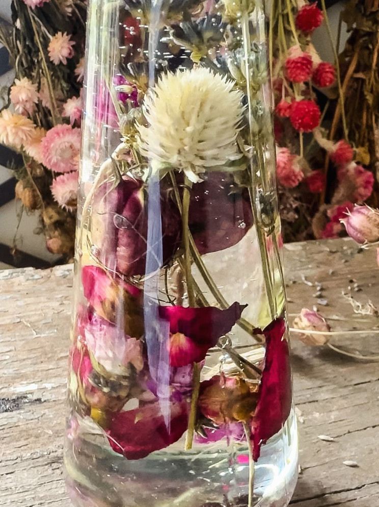 close up photo of a flower herbarium bottle with white and red flowers