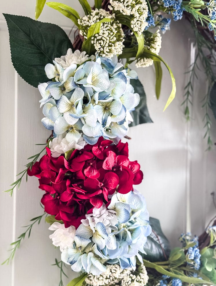 detail photo of a faux flower wreath with red and blue hydrangeas