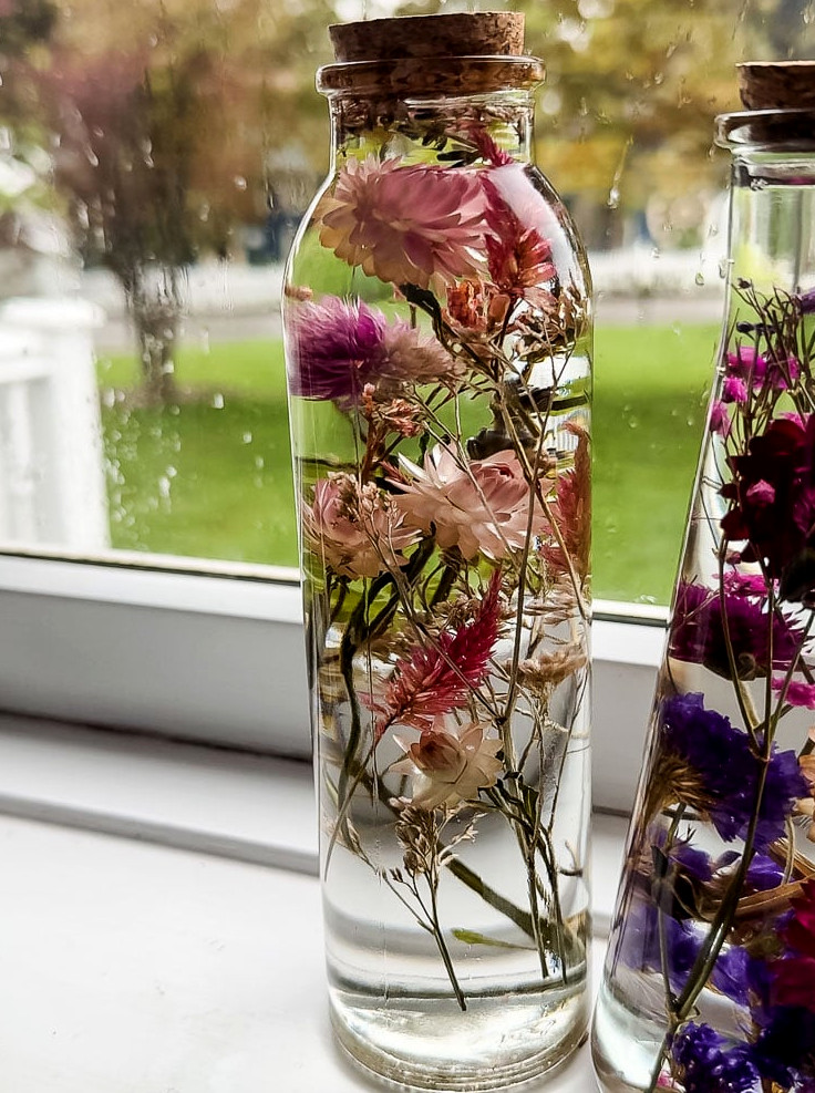 glass herbarium bottle in window filled with pink flowers