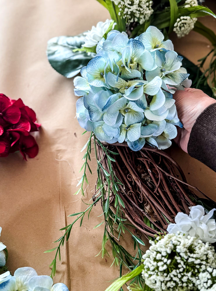 hand gluing a hydrangea stem to a wreath