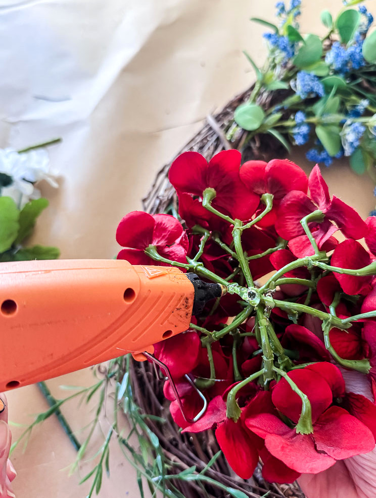 hot glue going on back of red hydrangea faux flower